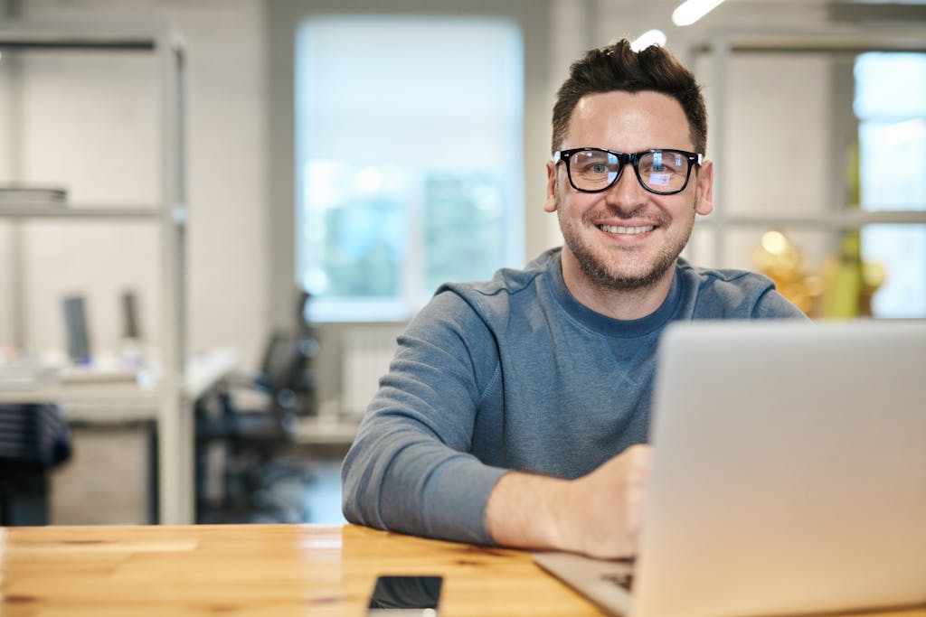 Happy man wearing glasses working remotely on laptop in an adult literacy program